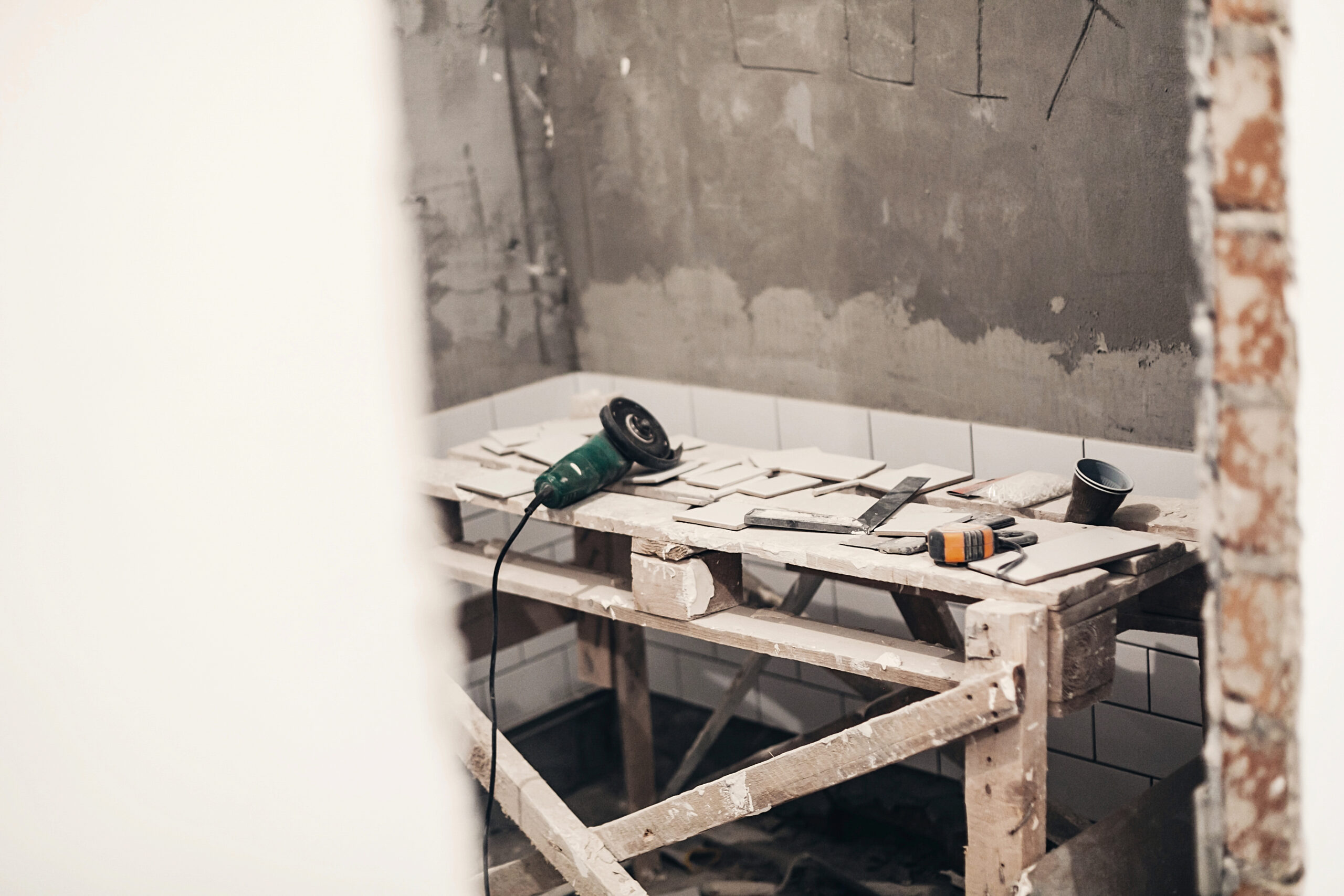 grinder and stylish white tiles for cutting. renovation concept. ceramic tiles  and grey cement walls in bathroom, renovating and working in toilet, space for text